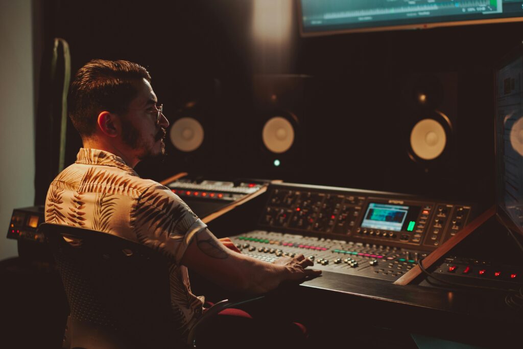 pexels-photo-7586137-7586137 Audio engineer focused on mixing at a professional sound console in a dimly lit recording studio.